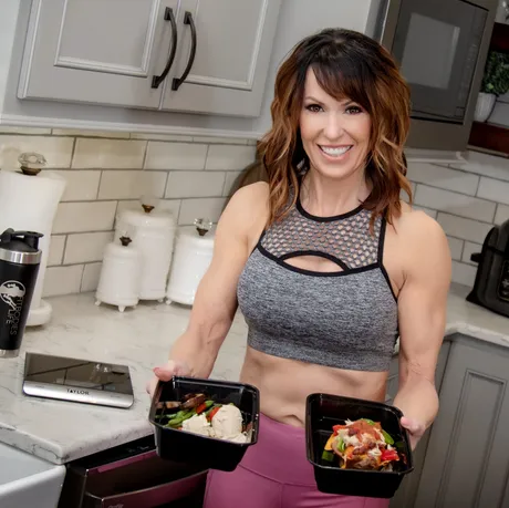 Woman in Kitchen Holding Cooked Meals in Both Hands